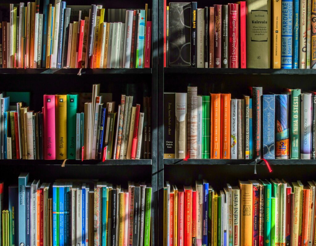 A bookshelf filled with rows of colorful books arranged vertically and horizontally on dark shelves.